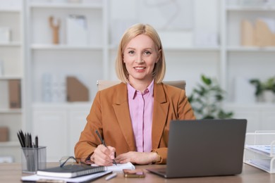 Portrait of smiling middle aged woman at table in office