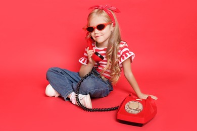 Photo of Cute little girl with telephone on red background