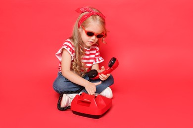 Photo of Cute little girl with telephone on red background