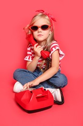 Cute little girl with telephone on red background