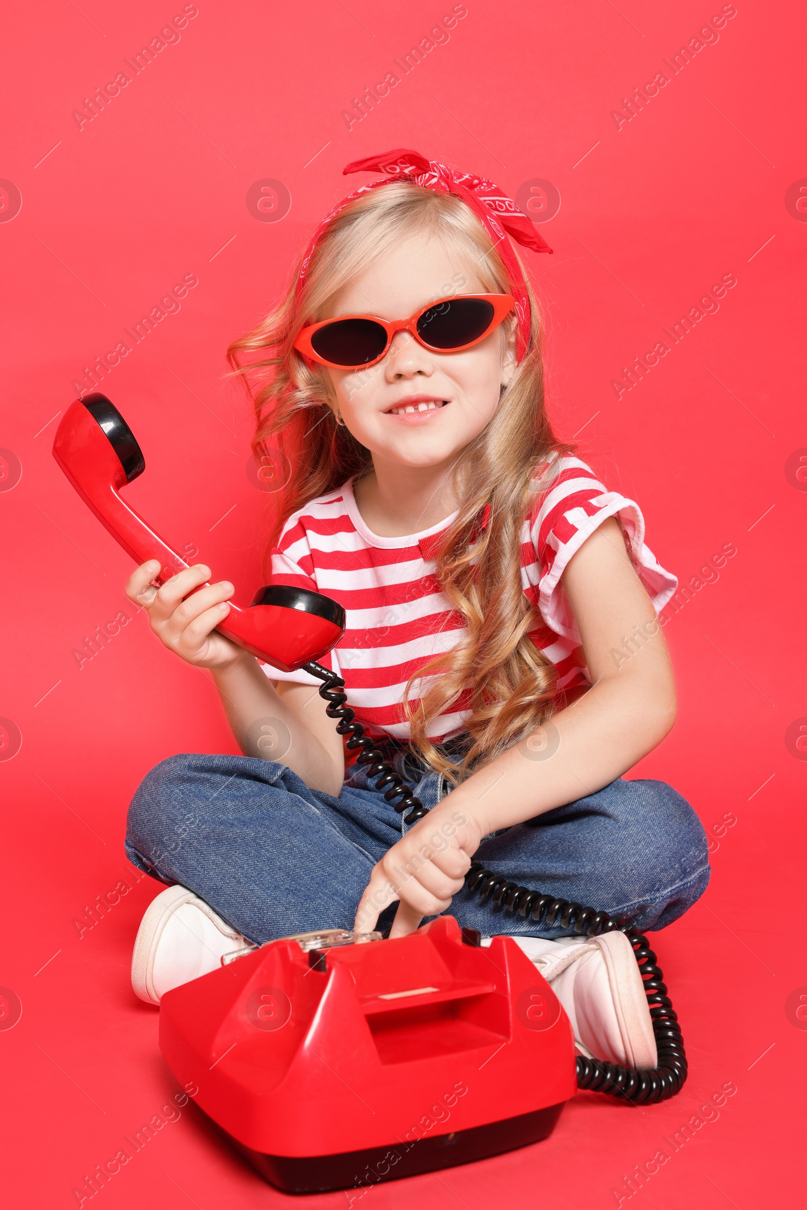 Photo of Cute little girl with telephone on red background