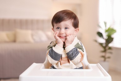 Photo of Cute little kid sitting in high chair at home