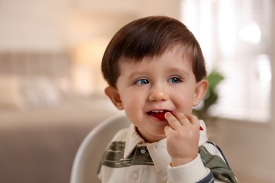 Photo of Cute little baby eating healthy food in high chair at home