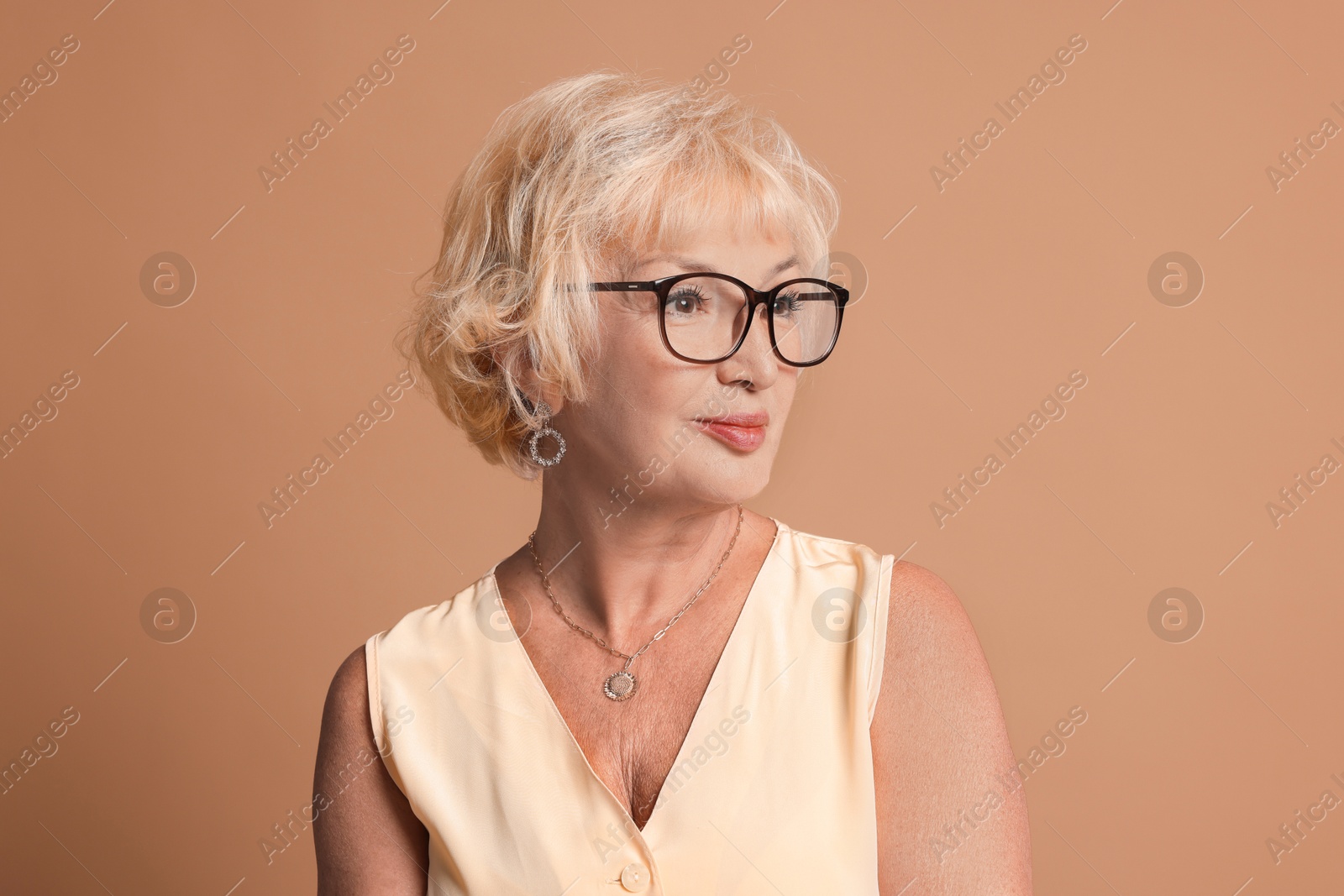 Photo of Portrait of beautiful senior woman on light brown background