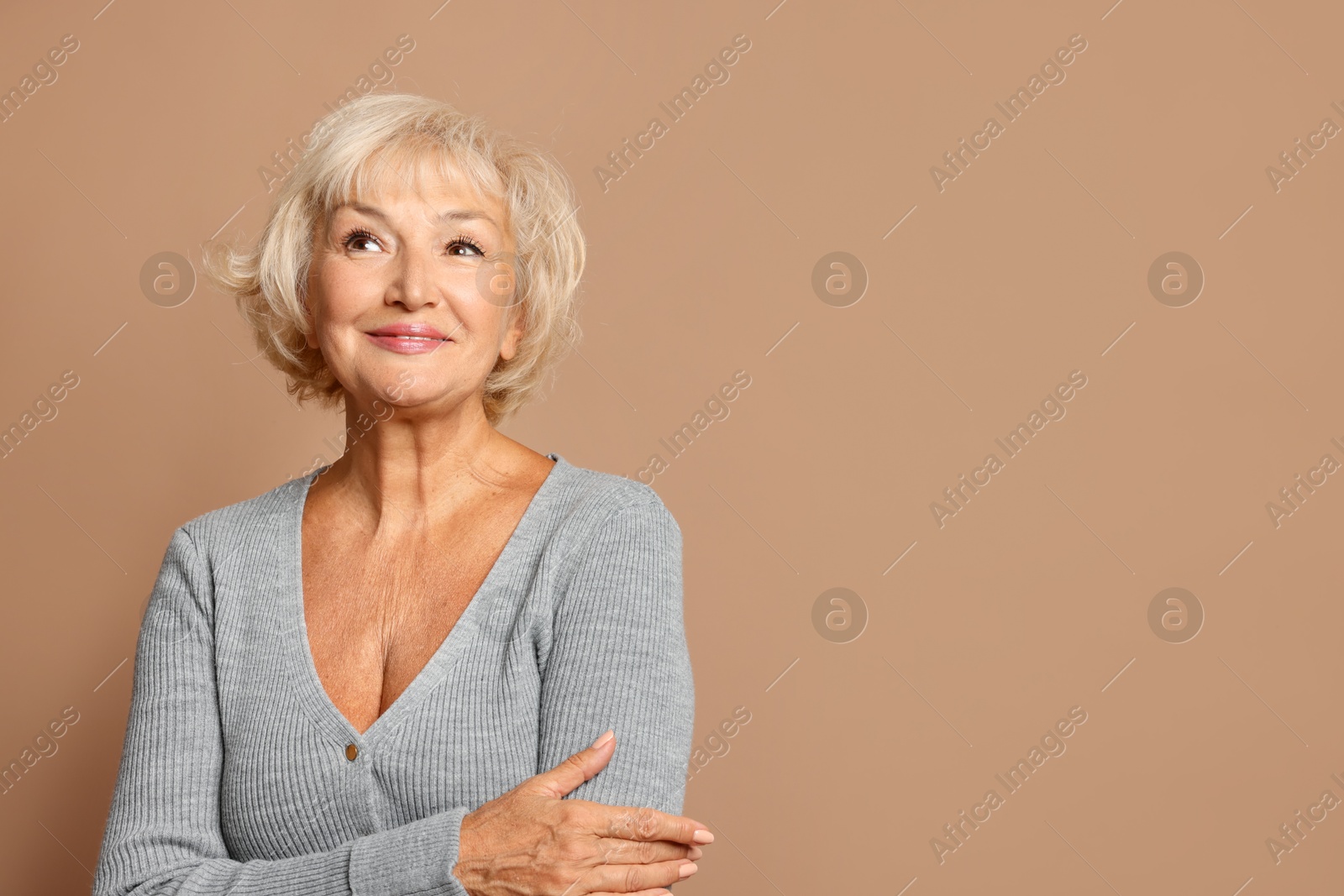 Photo of Portrait of beautiful senior woman on light brown background, space for text