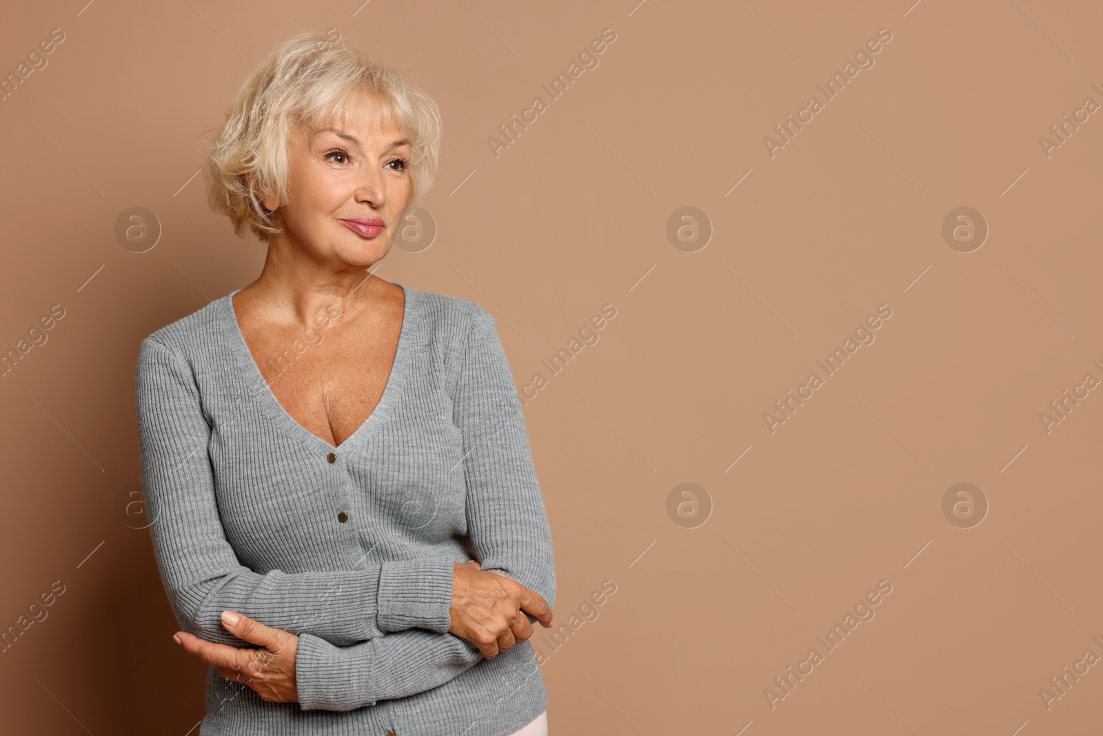 Photo of Portrait of beautiful senior woman on light brown background, space for text