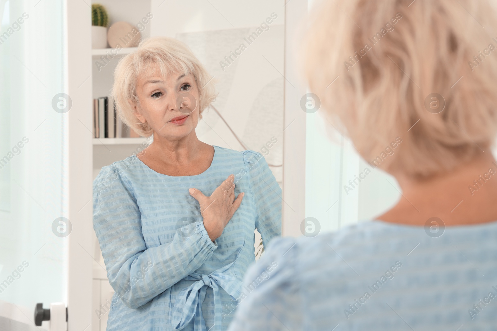 Photo of Beautiful senior woman near mirror at home