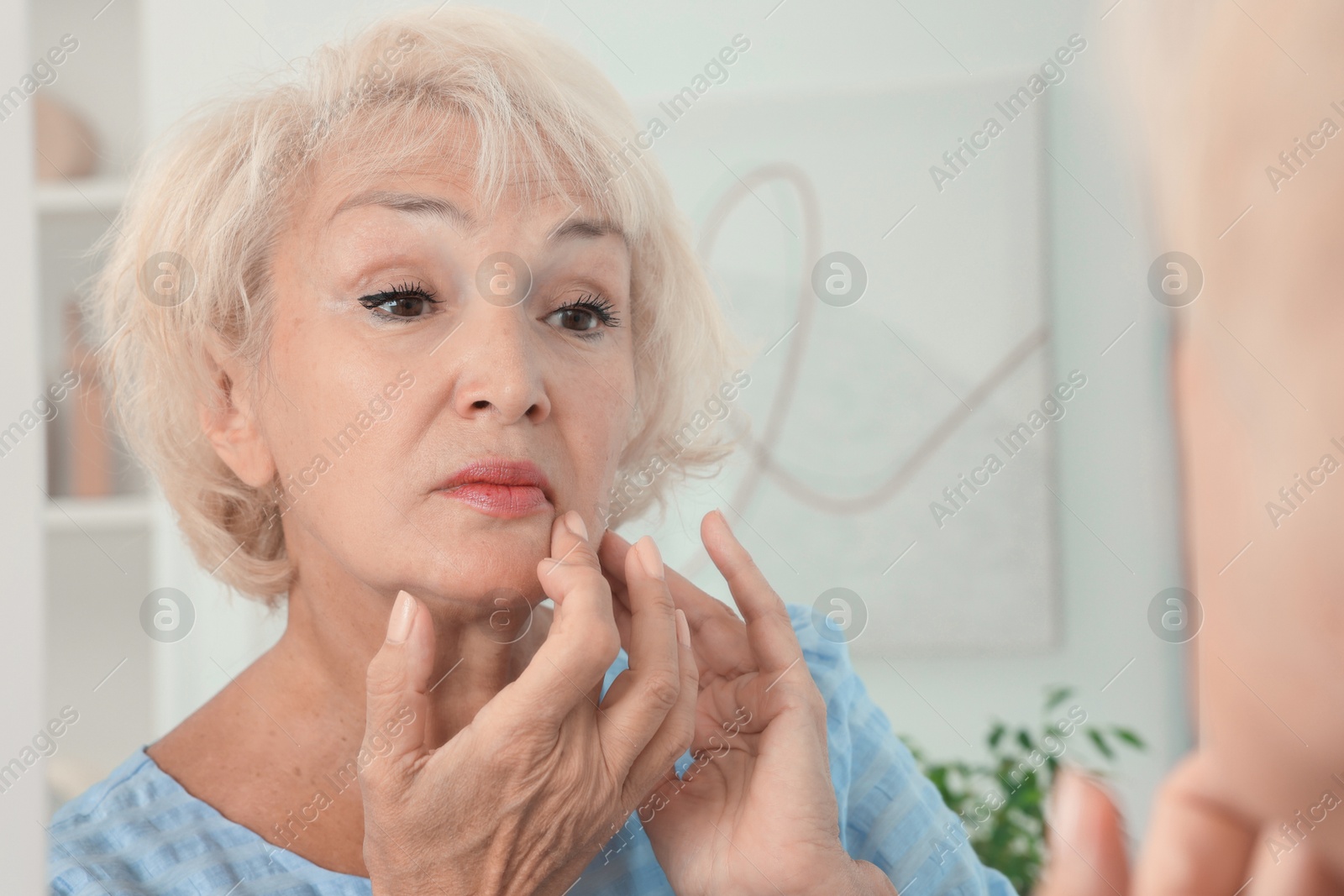 Photo of Beautiful senior woman near mirror at home