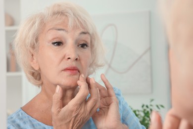 Photo of Beautiful senior woman near mirror at home