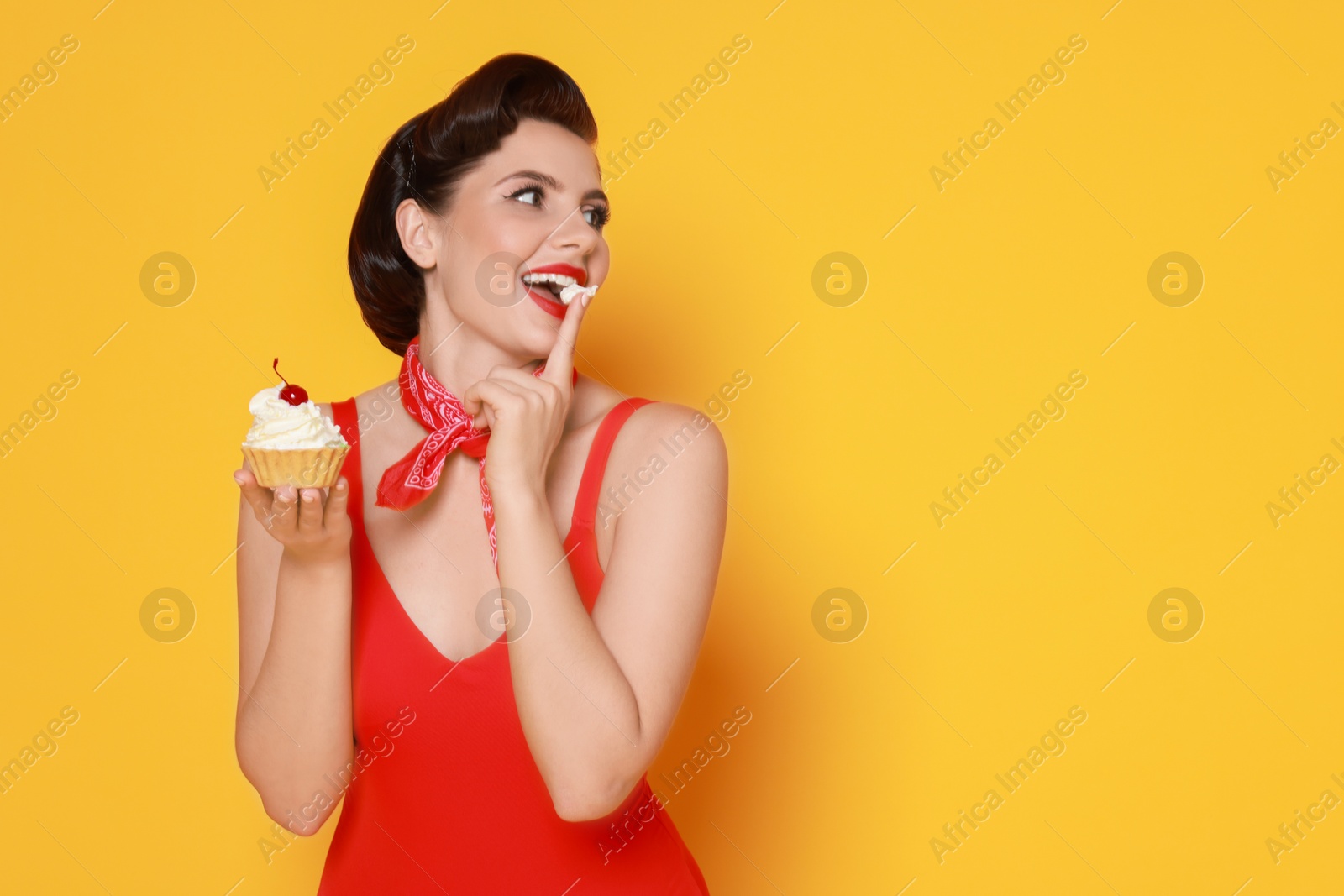 Photo of Pin-up woman eating cupcake on orange background, space for text