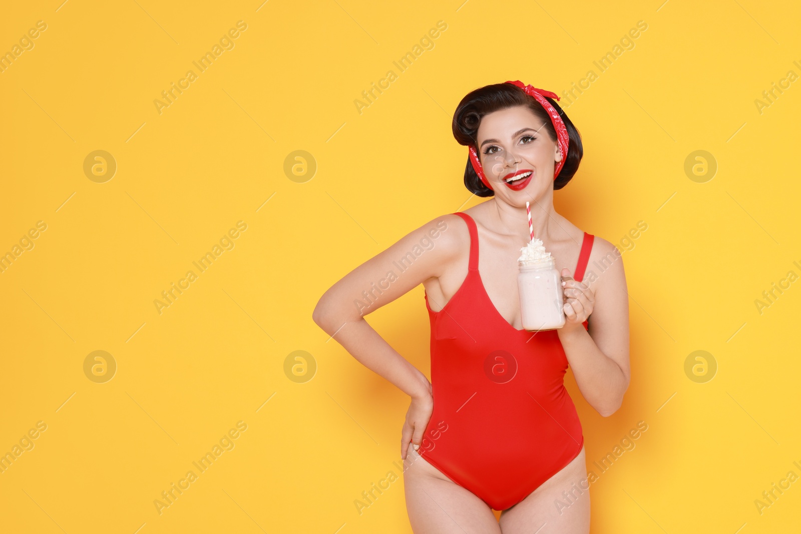 Photo of Pin-up woman in swimsuit with milk shake on orange background, space for text