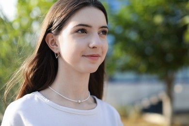 Photo of Portrait of beautiful teenage girl on city street. Space for text