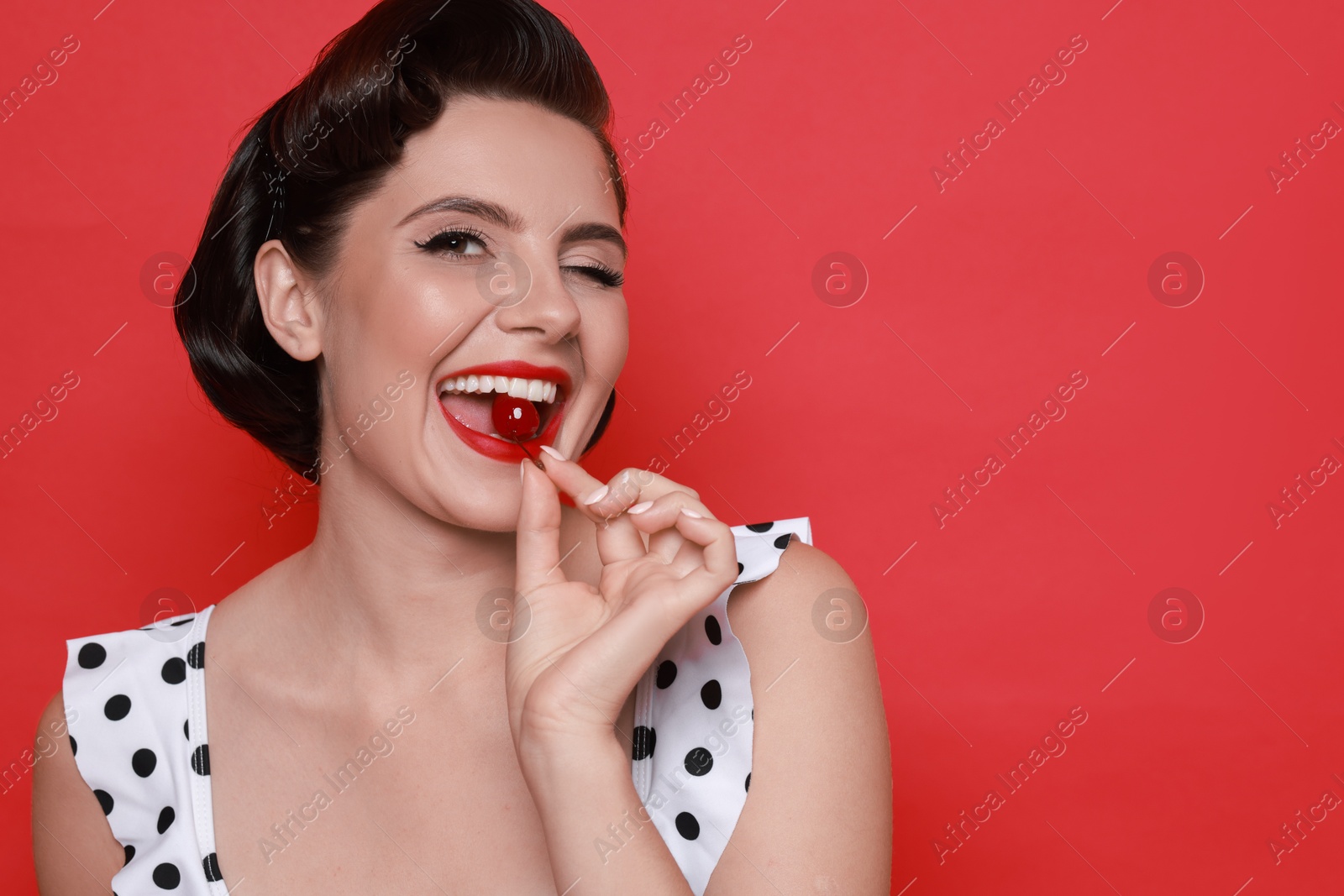 Photo of Pin-up woman eating cherry on red background, space for text