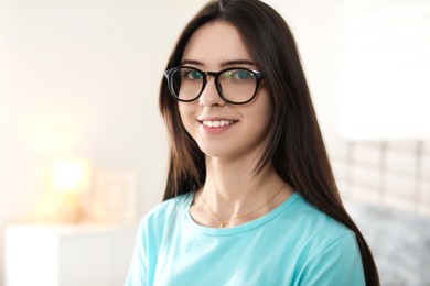 Portrait of happy teenage girl in glasses at home