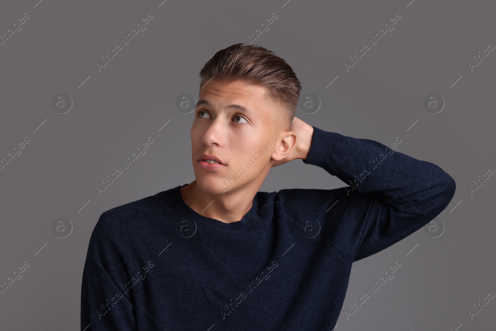 Photo of Handsome young man with stylish haircut on grey background