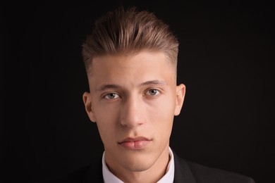 Photo of Confident young man with stylish haircut on black background