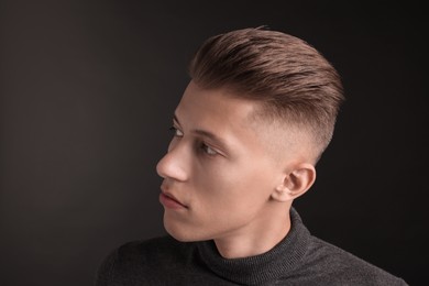 Photo of Handsome young man with stylish haircut on black background