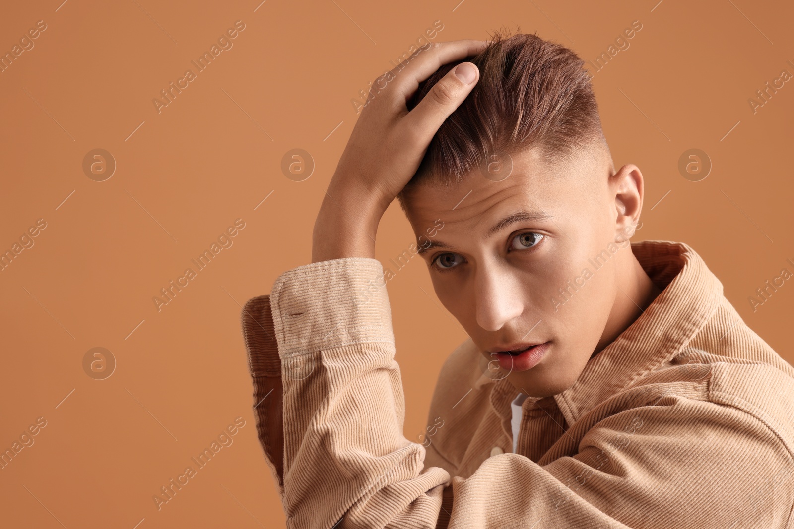 Photo of Confident young man with stylish haircut on brown background