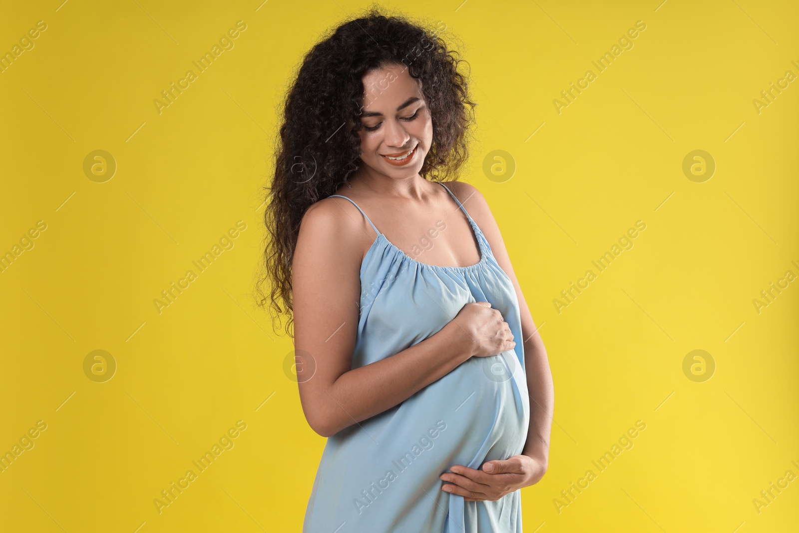 Photo of Portrait of beautiful pregnant woman on yellow background