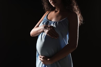 Photo of Pregnant woman on black background, closeup view