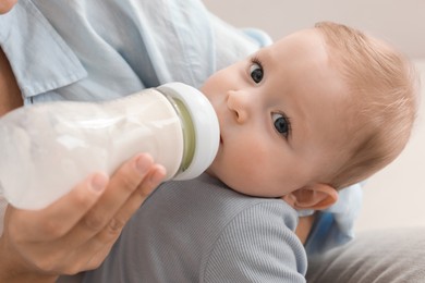 Photo of Mother feeding her little baby from bottle, closeup