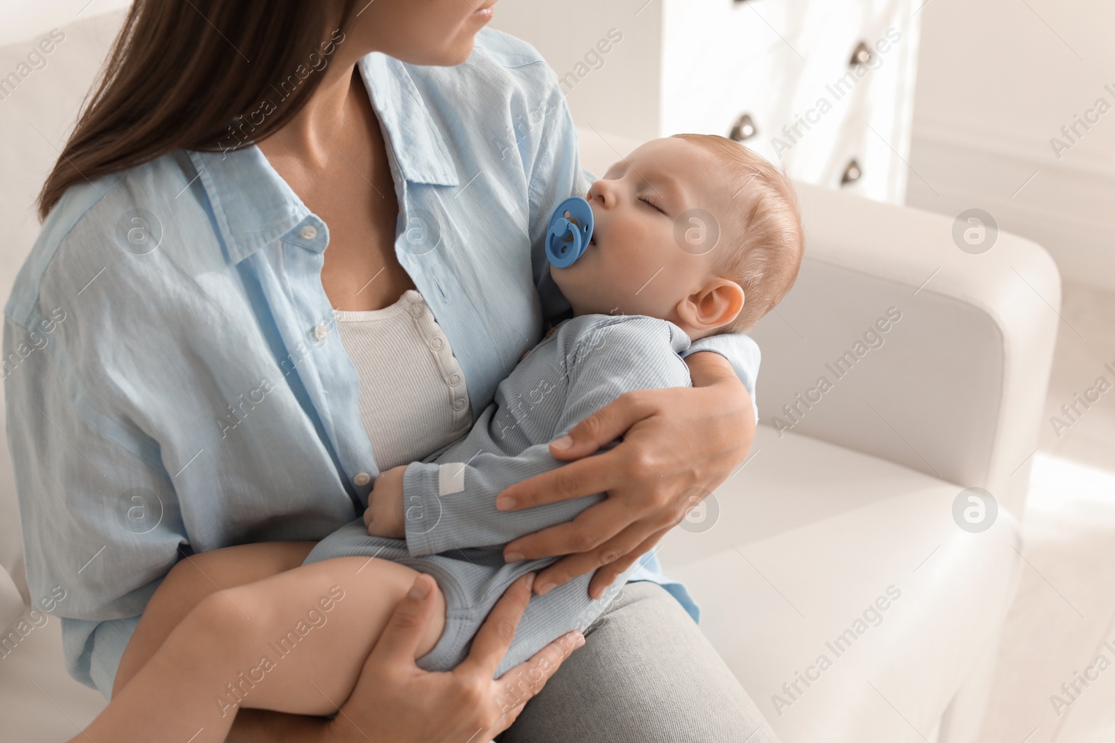 Photo of Mother with her sleeping baby on sofa indoors, closeup