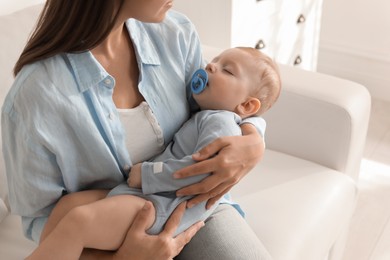 Photo of Mother with her sleeping baby on sofa indoors, closeup