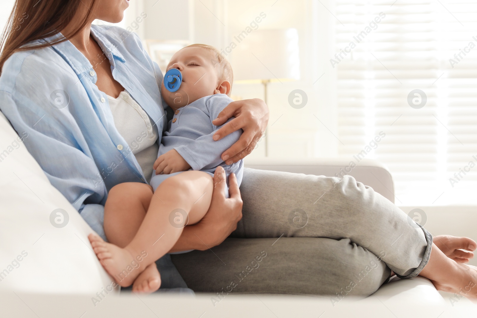 Photo of Mother with her sleeping baby on sofa indoors, closeup