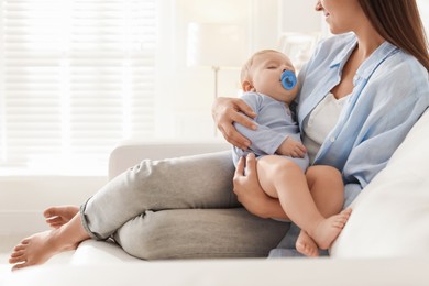 Photo of Mother with her sleeping baby on sofa indoors, closeup