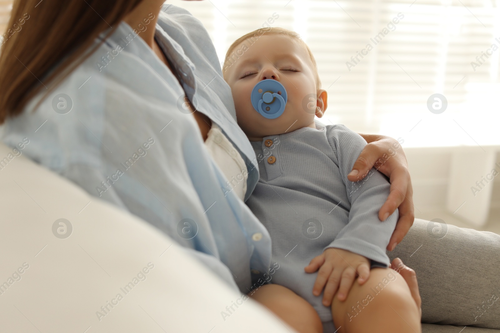 Photo of Mother with her sleeping baby on sofa indoors, closeup