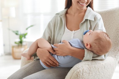 Photo of Mother with her sleeping baby in armchair at home, closeup