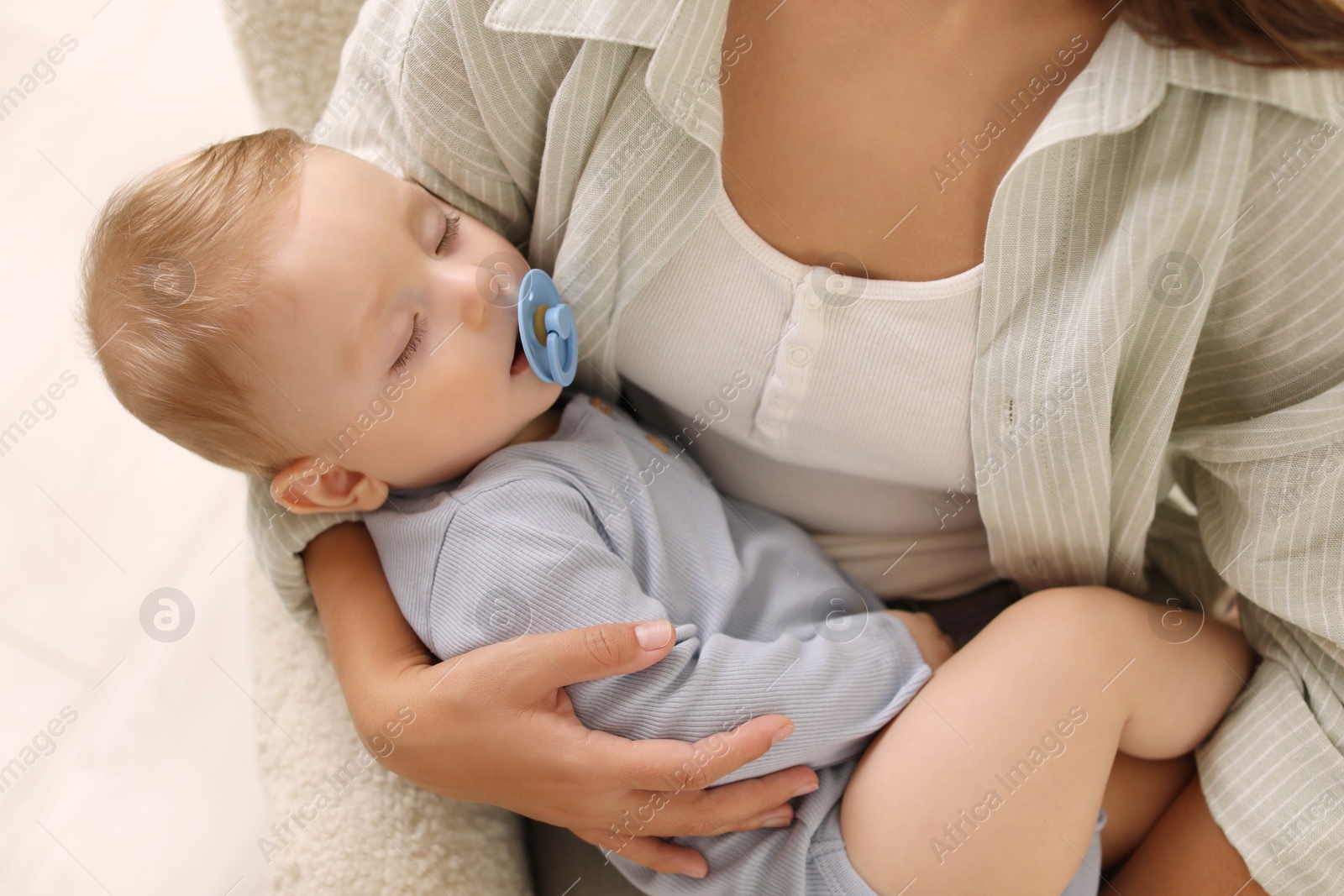 Photo of Mother with her sleeping baby in armchair indoors, closeup