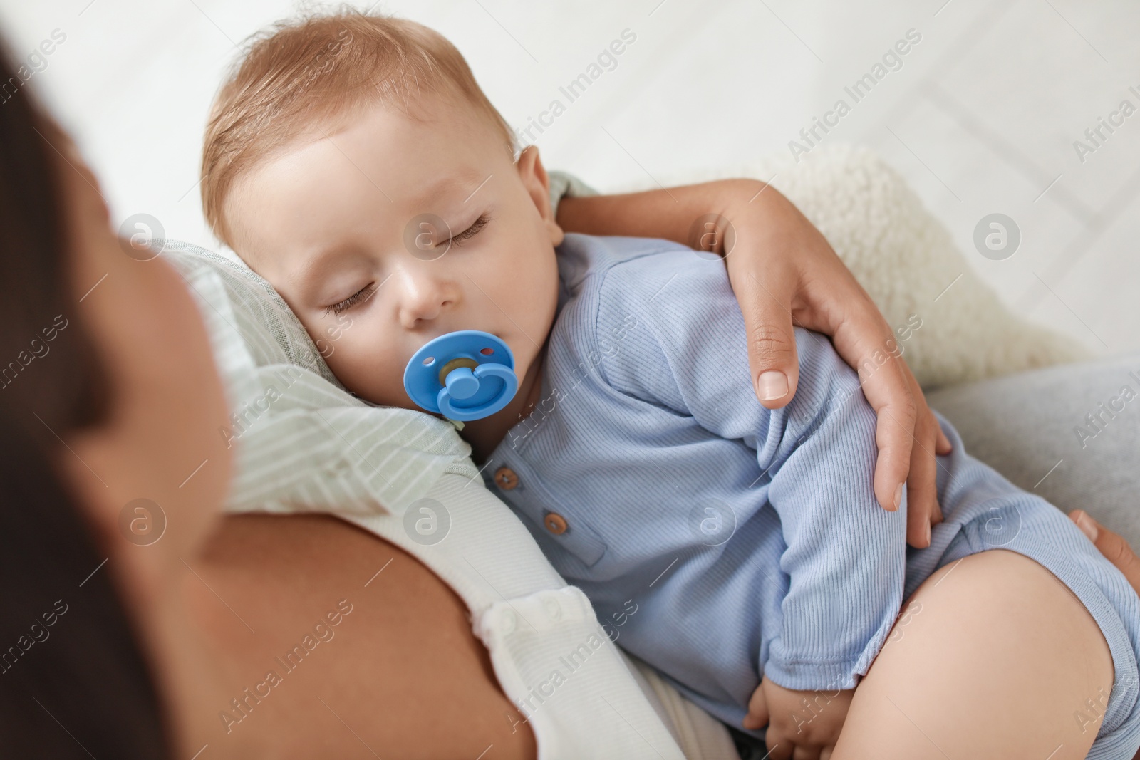 Photo of Mother with her sleeping baby in armchair indoors