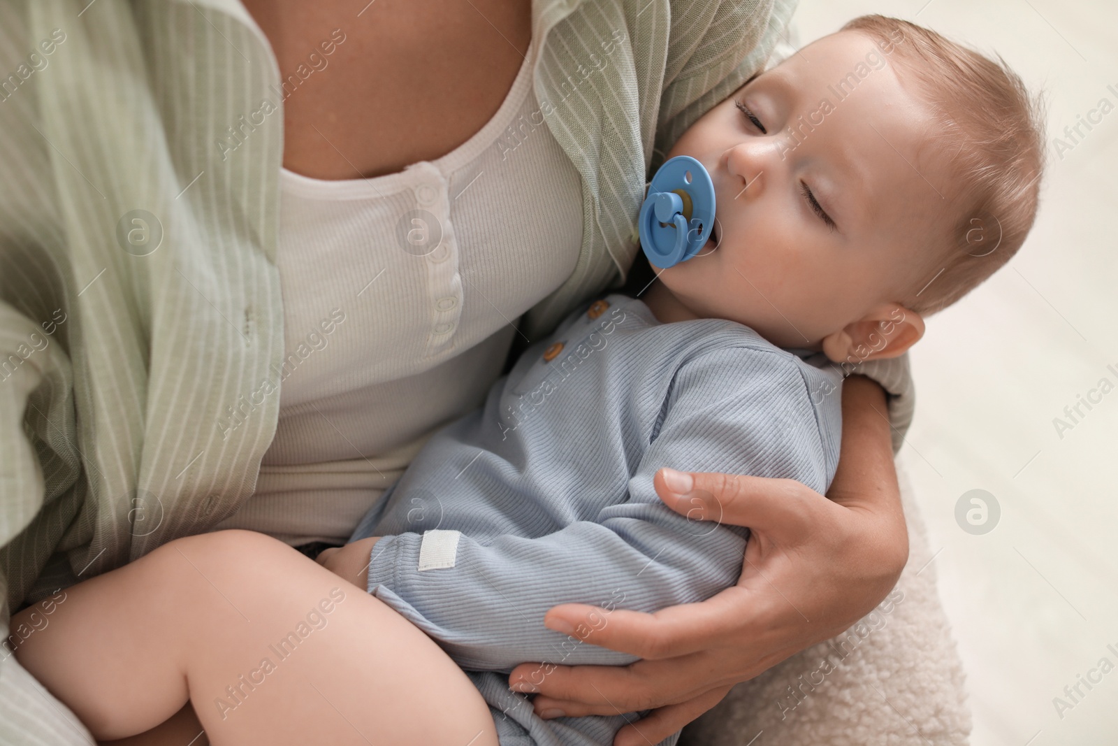 Photo of Mother with her sleeping baby in armchair indoors, closeup