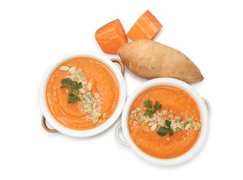 Photo of Delicious sweet potato soup with pumpkin seeds in bowls and fresh vegetable isolated on white, top view