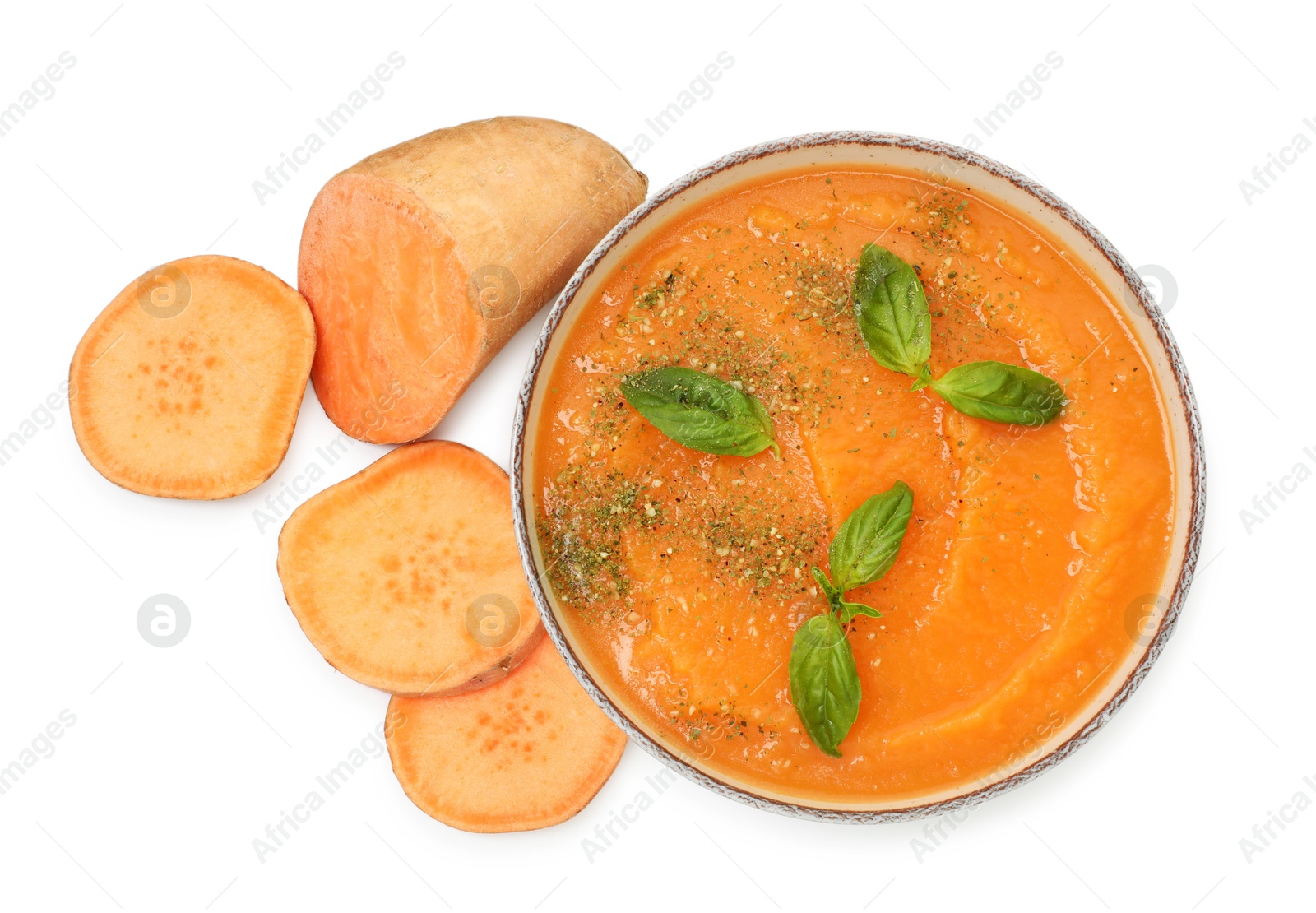 Photo of Delicious sweet potato soup with basil in bowl and fresh vegetable isolated on white, top view