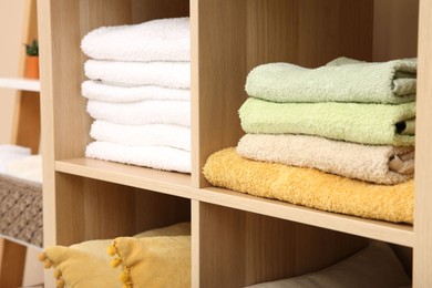 Photo of Folded towels on shelving unit indoors. Home textile storage