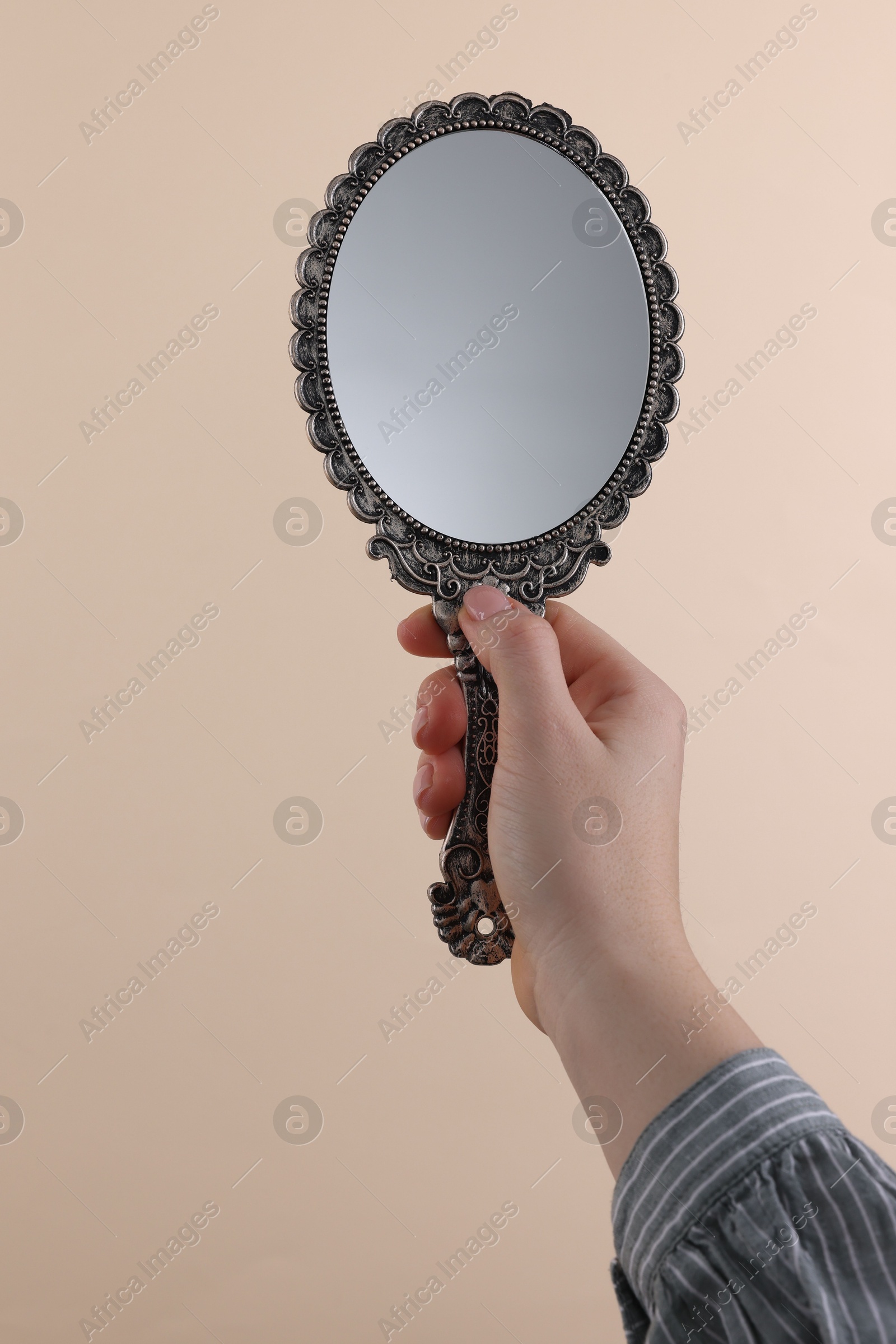 Photo of Woman holding beautiful mirror on beige background, closeup