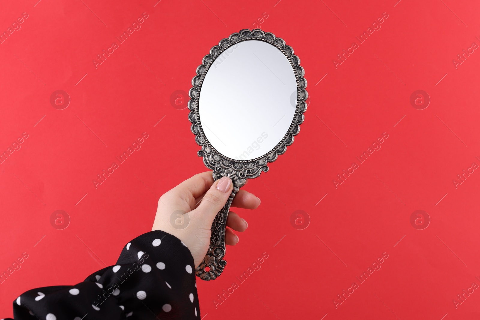 Photo of Woman holding beautiful mirror on red background, closeup