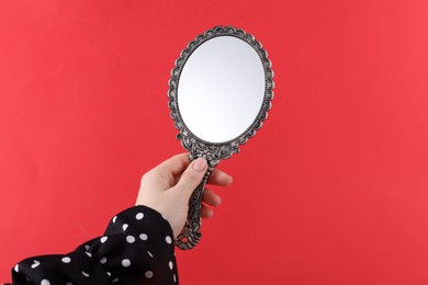 Woman holding beautiful mirror on red background, closeup