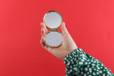 Photo of Woman holding pocket mirror on red background, closeup