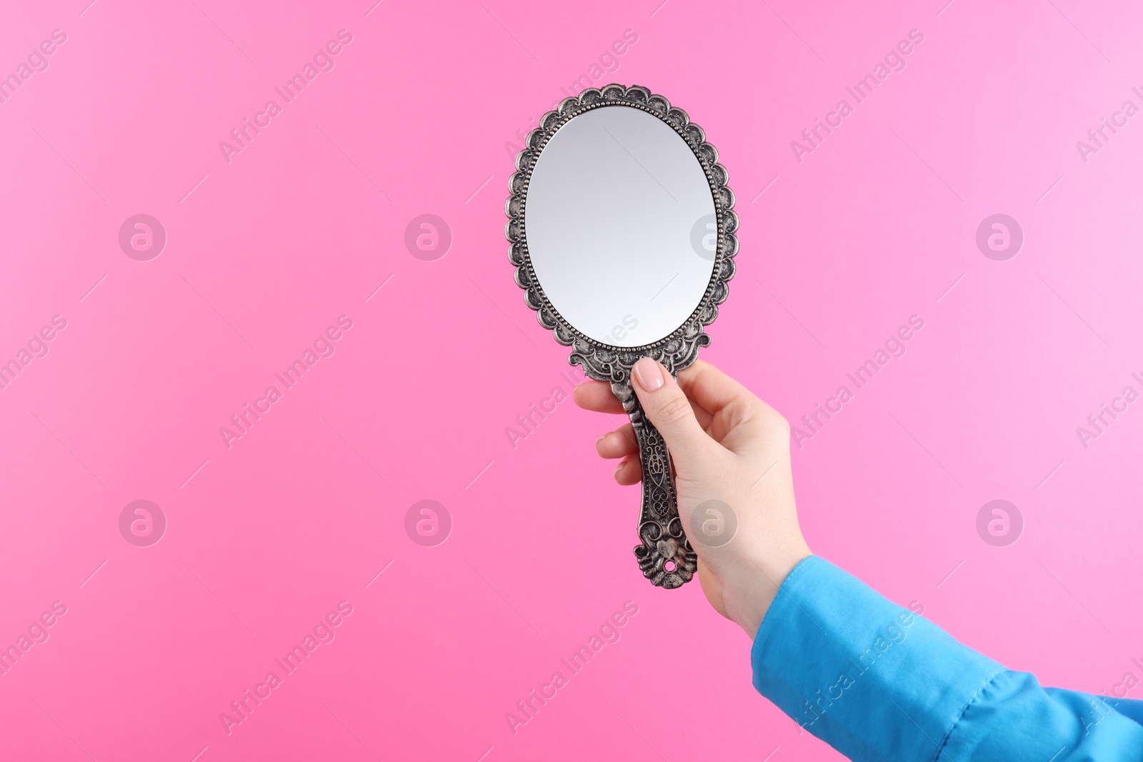 Photo of Woman holding beautiful mirror on pink background, closeup. Space for text