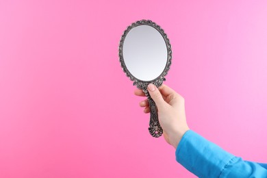 Woman holding beautiful mirror on pink background, closeup. Space for text