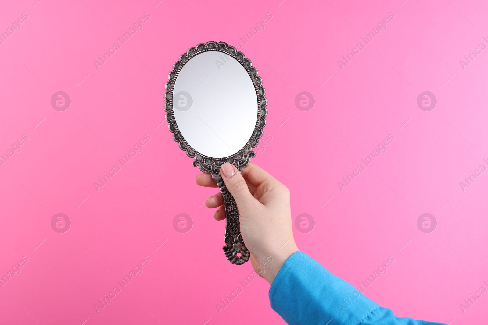 Photo of Woman holding beautiful mirror on pink background, closeup