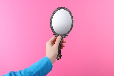 Photo of Woman holding beautiful mirror on pink background, closeup