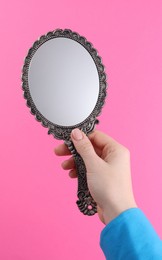 Woman holding beautiful mirror on pink background, closeup