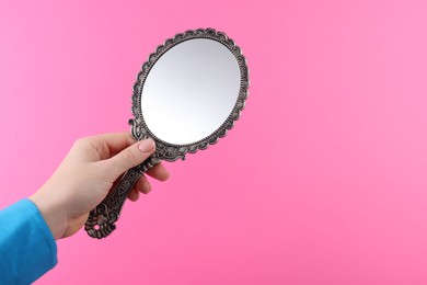 Photo of Woman holding beautiful mirror on pink background, closeup. Space for text