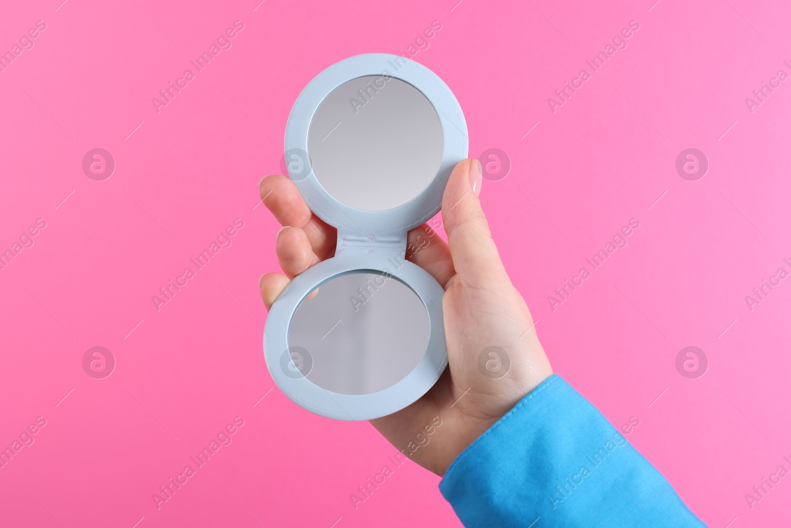 Photo of Woman holding pocket mirror on pink background, closeup