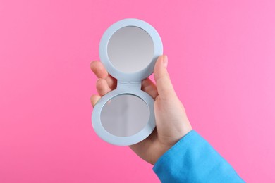 Photo of Woman holding pocket mirror on pink background, closeup