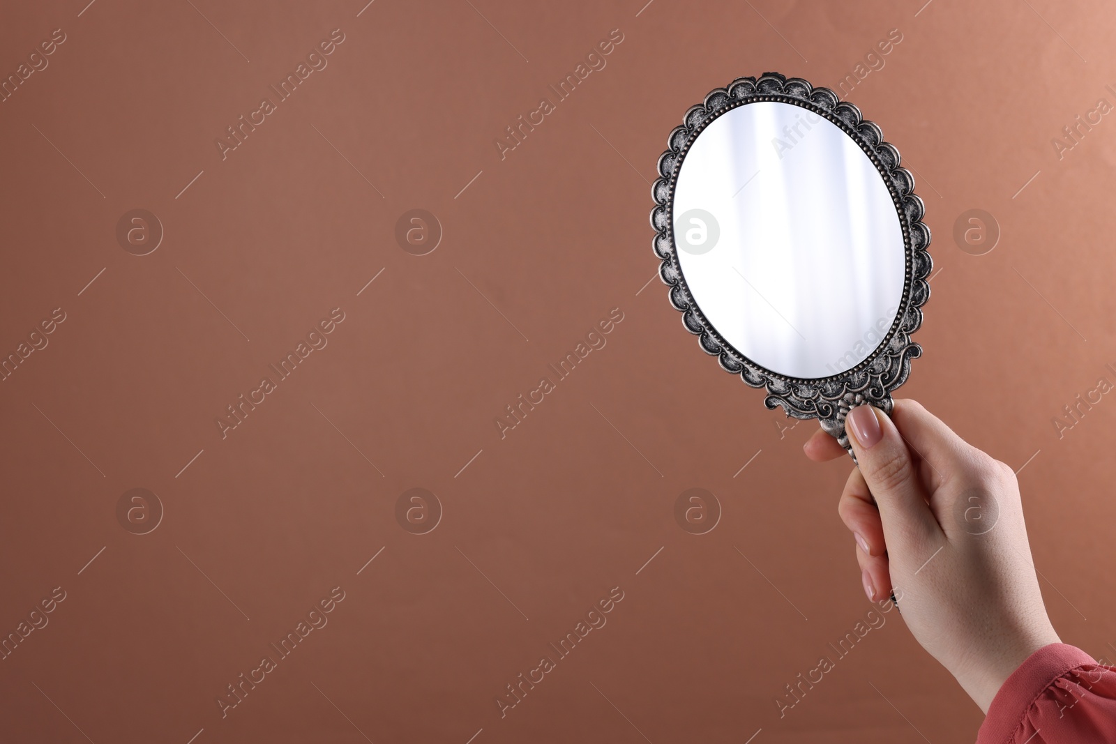 Photo of Woman holding beautiful mirror on beige background, closeup. Space for text